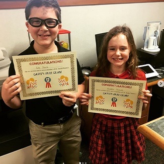 Two children holding cavity free club certificates