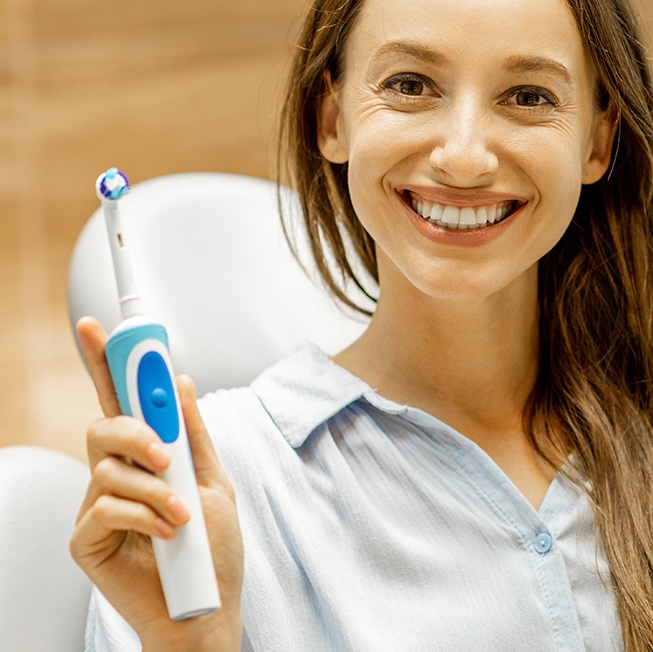 Woman holding up sonicare toothbrush