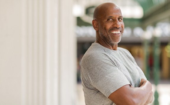 Man in gray shirt smiling outside