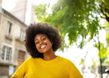 Woman in yellow shirt standing outside smiling