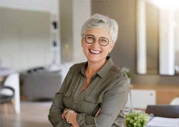 Senior woman with glasses smiling with arms folded