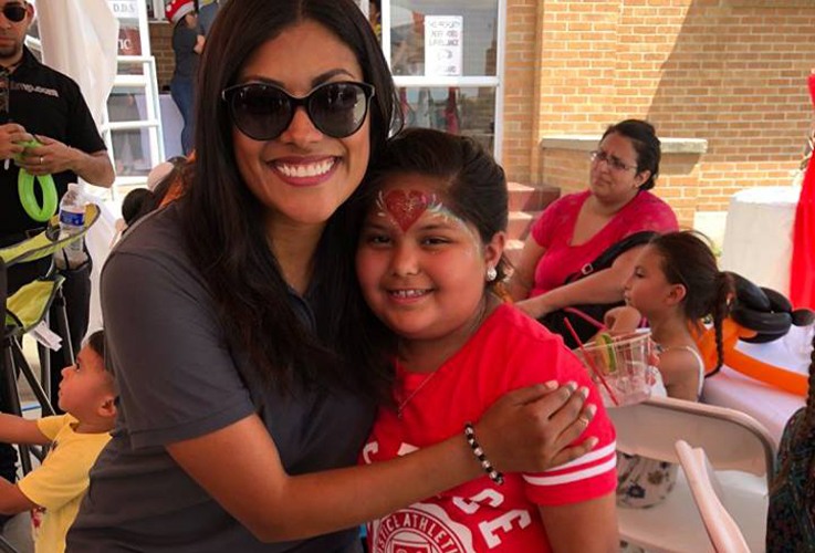 Doctor Pitarra taking a picture with a young patient at community event