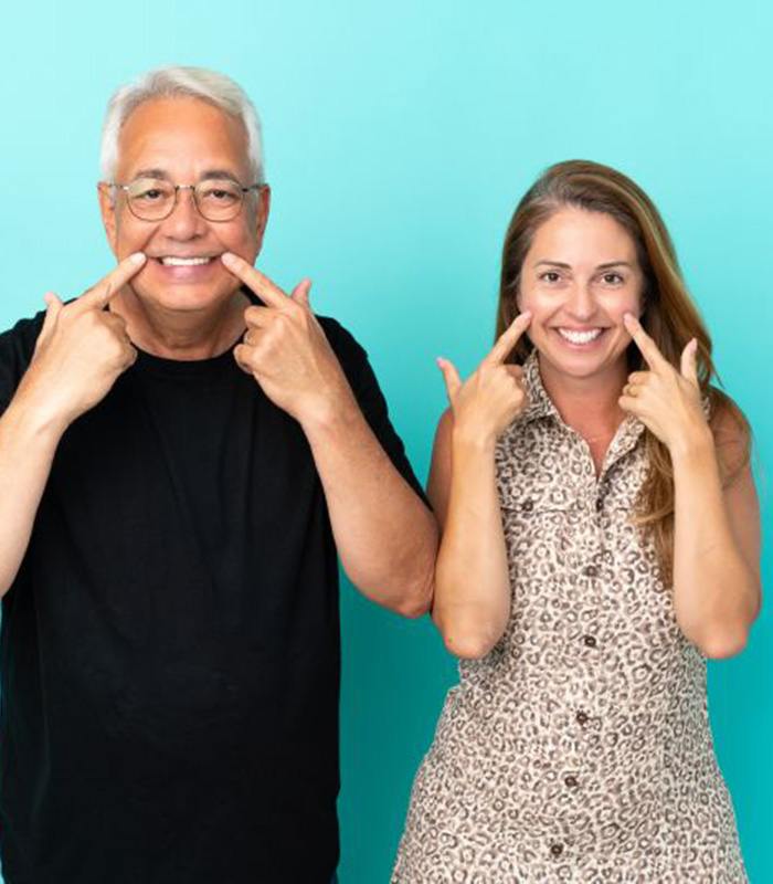 Happy middle-aged couple pointing at their teeth