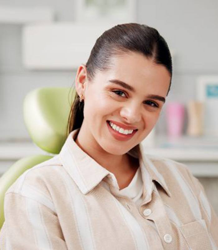 Happy young woman in dental treatment chair
