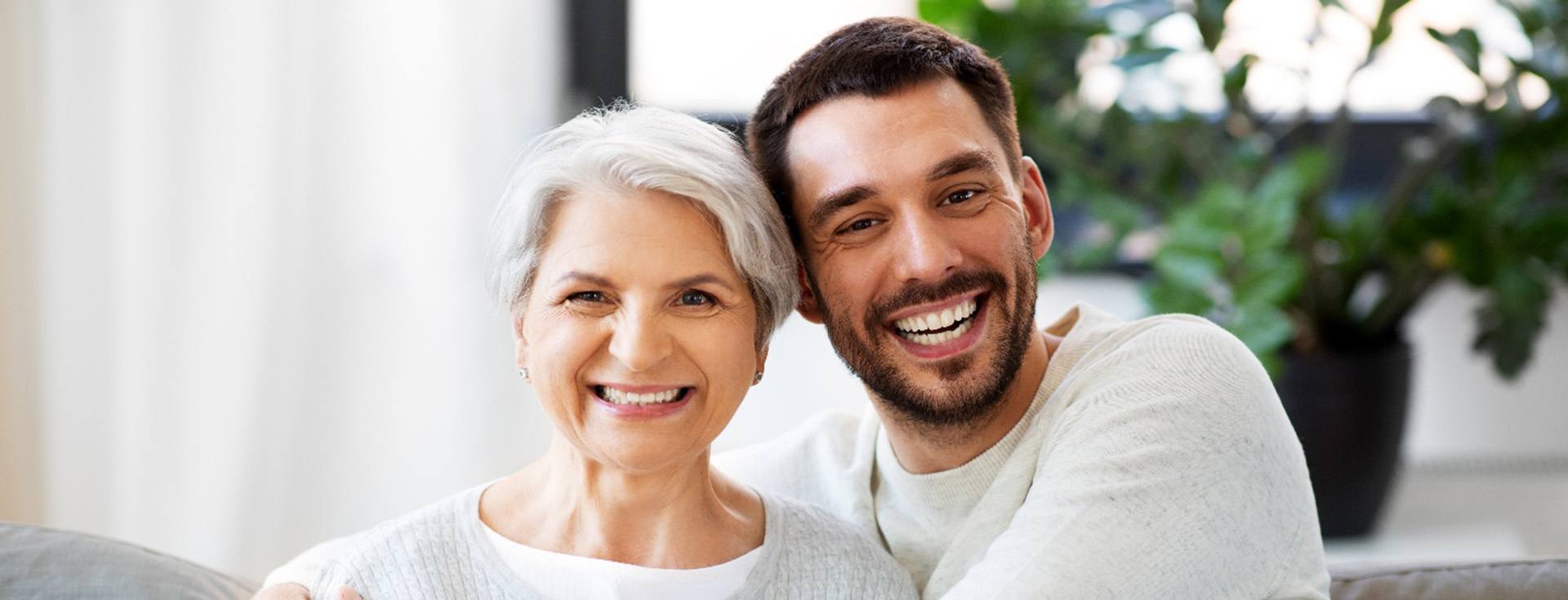 Man and woman on couch smiling with his arms around her