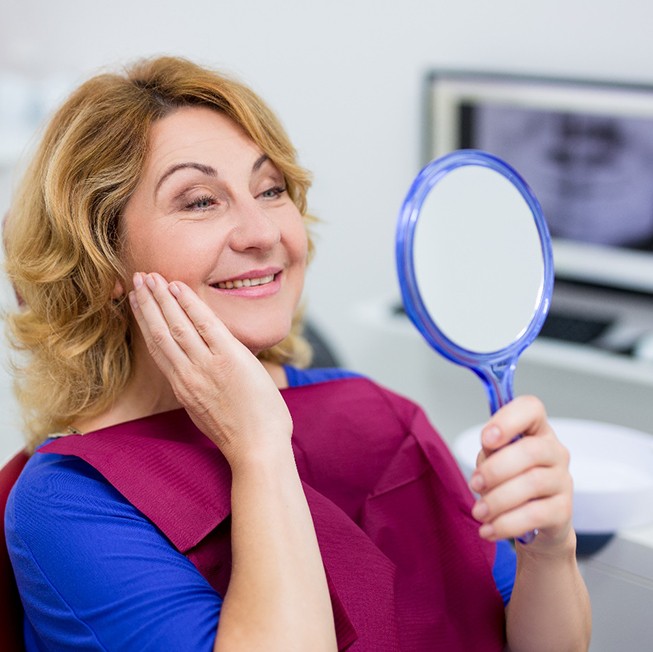  woman seeing her new smile after getting dental implants in Corpus Christi 