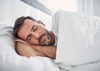 man sleeping in a bed on his side 