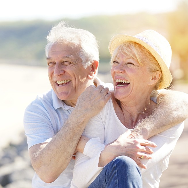 Older man and woman laughing after dental implant tooth replacement