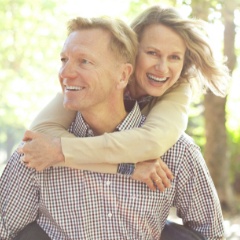 Man and woman smiling after replacing missing teeth