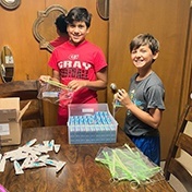 Two kids putting together oral healthcare product bags
