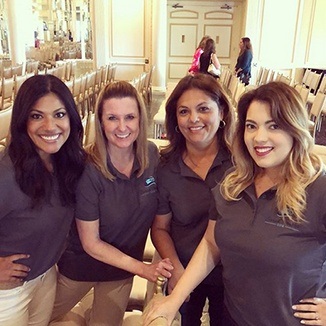 Four dental team members smiling at even