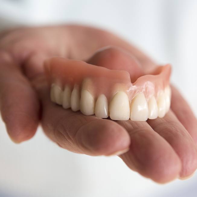 Hand holding a full denture