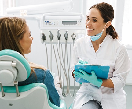Smiling dentist taking notes on clipboard