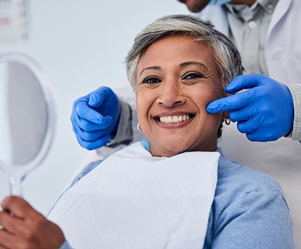 Woman smiling while holding handheld mirror