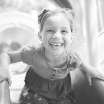 Little girl smiling at playground after children's dentistry treatment