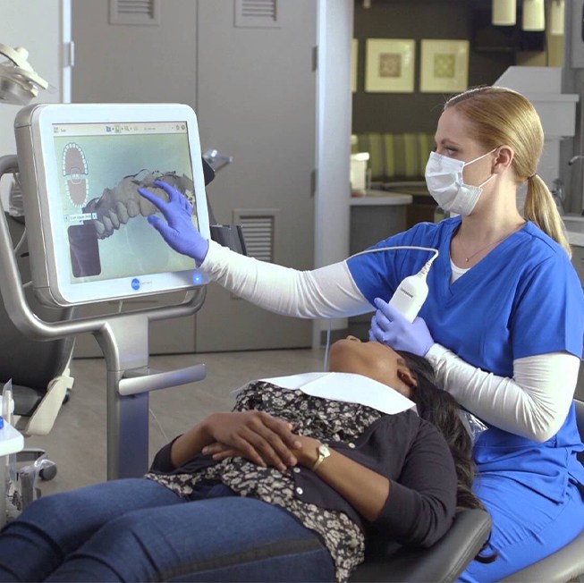 Dental team member and patient looking at intraoral images on computer screen
