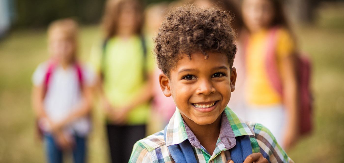 Young boy carrying his backpack and smiling after lip and tongue-tie treatment in Corpus Christ