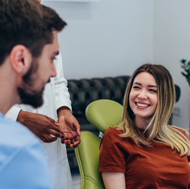 Patient in brown shirt smiling at dentist during consultation