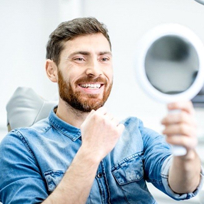 patient holding veneers up to her smile