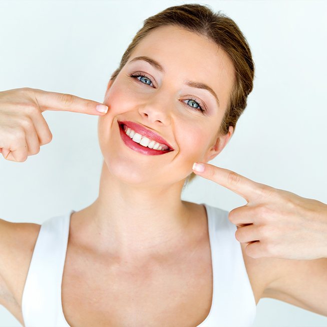 Woman pointing to flawless smile after teeth whitening